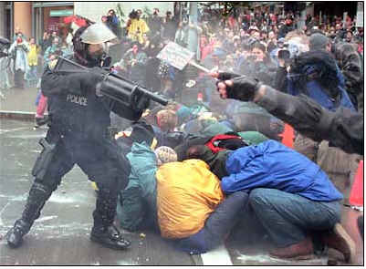 Policeman shooting a plastic pellet weapon at demonstrators in seattle